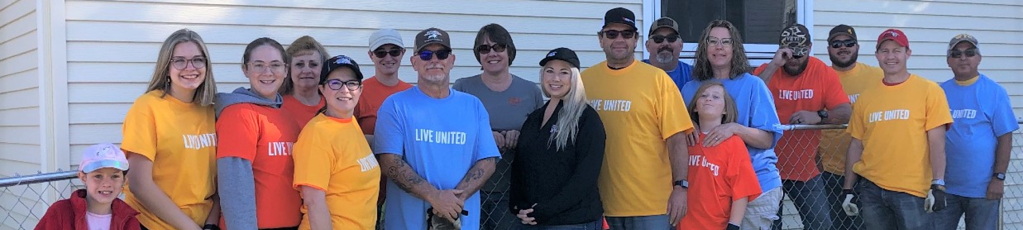 group of adults and wearing wearing Live United tshirts in in front of a building