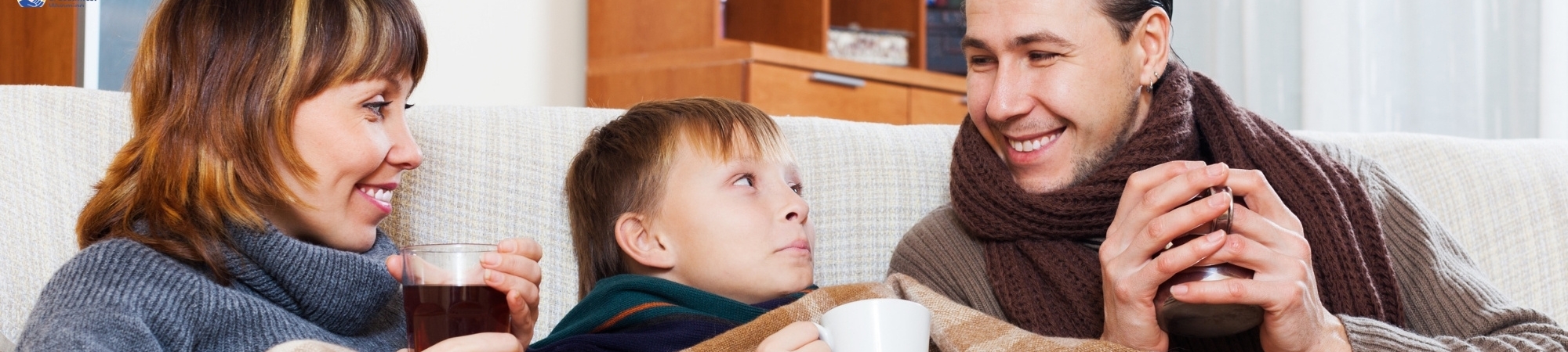 Family sitting on the couch sipping hot drinks